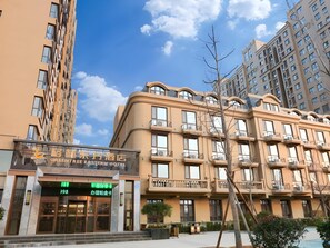 A hotel with a modern facade, multiple balconies, and a clear sky.