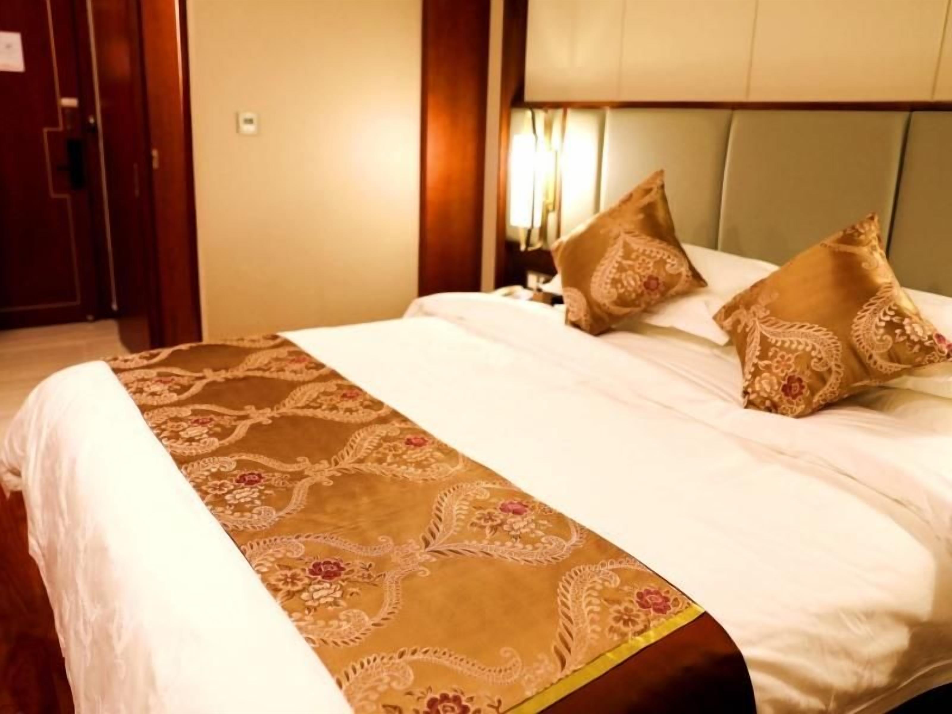 Una habitación de hotel con una cama, cabecera y mesita de noche.