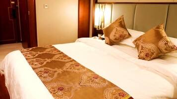 Una habitación de hotel con una cama, cabecera y mesita de noche.