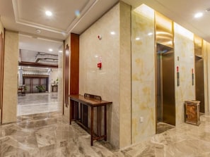 Un vestíbulo de hotel con piso de mármol, una recepción y un ascensor.