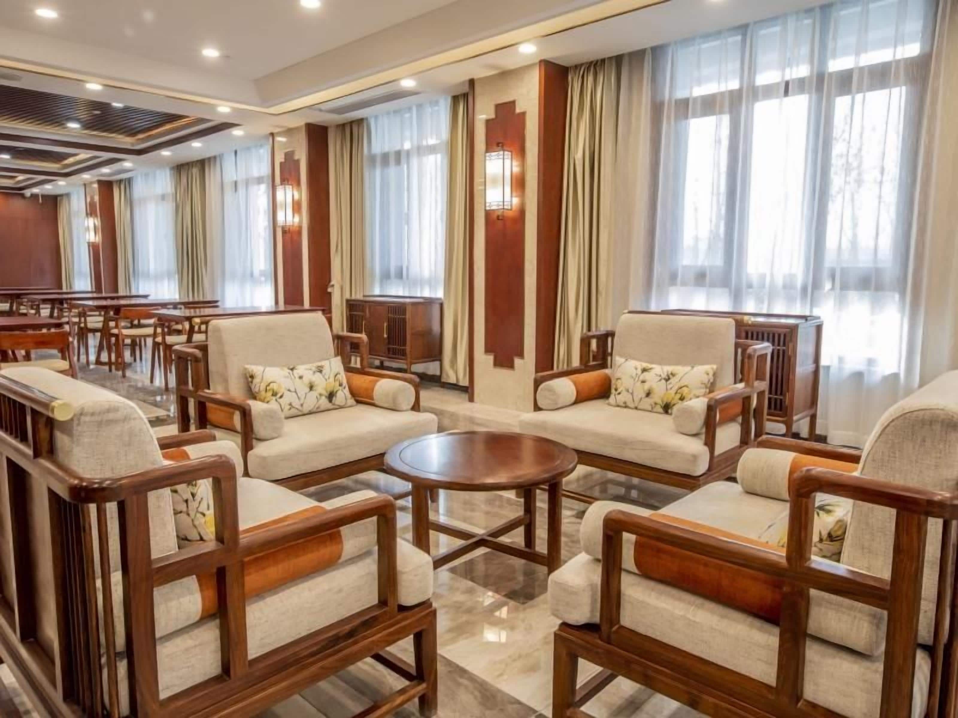 Un vestíbulo de hotel con varias zonas de estar, que incluyen sofás y sillones, dispuestos alrededor de una mesa de centro.
