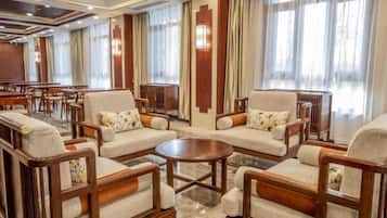 Eine Hotelhalle mit mehreren Sitzbereichen, darunter Sofas und Sessel, die um einen zentralen Couchtisch angeordnet sind.