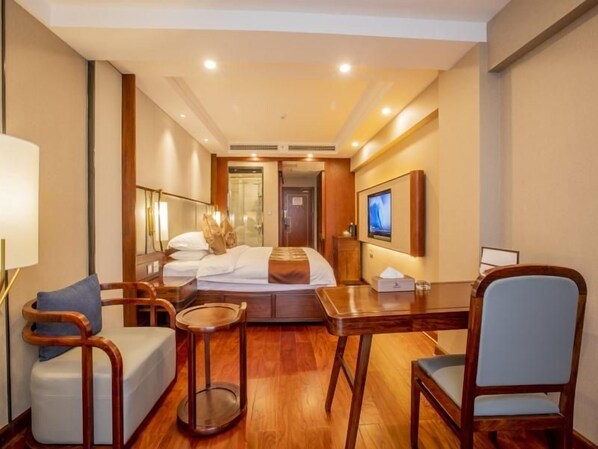 Una habitación de hotel con cama, escritorio, silla, mesita y televisor.