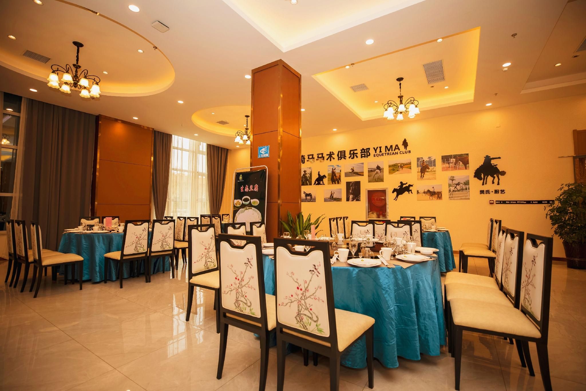A dining area with tables set for service, chairs with floral upholstery, and a wall adorned with equestrian-themed photographs.