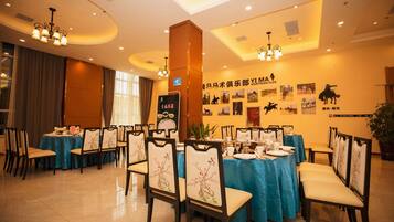 A dining area with tables set for service, chairs with floral upholstery, and a wall adorned with equestrian-themed photographs.