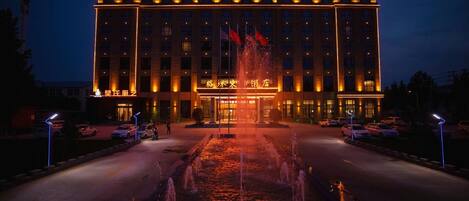 A hotel with a large entrance, a fountain in front, and multiple flags.