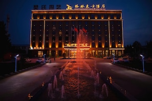 A hotel with a large entrance, a fountain in front, and multiple flags. - Greentree Eastern Xiangyang Zhongyuan West Road Hotel (Puyang)