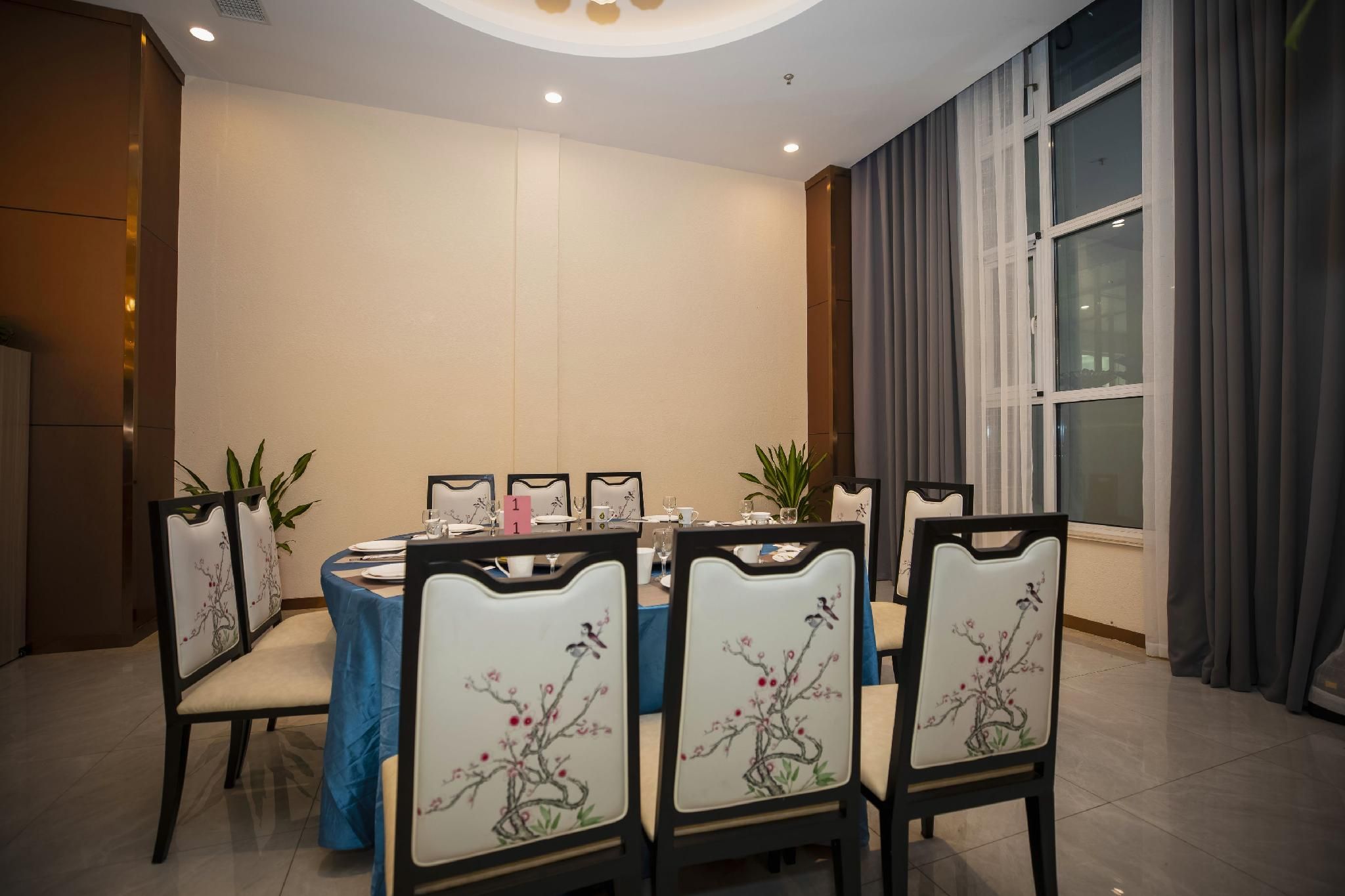 A conference room with a round table, chairs with floral upholstery, and a large window with curtains.