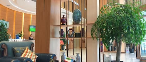 A lobby with a reception desk, seating area, and a large potted plant.
