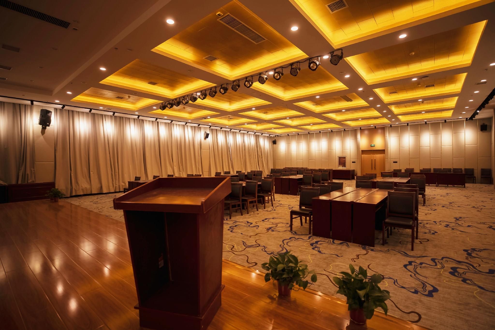 A conference room with a podium, tables, chairs, and a carpeted floor.