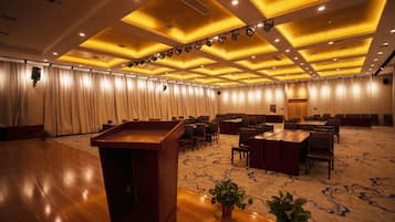 A conference room with a podium, tables, chairs, and a carpeted floor.