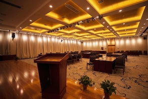 A conference room with a podium, tables, chairs, and a carpeted floor.