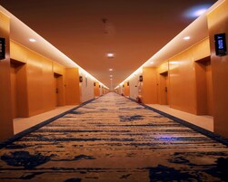Pasillo de hotel con suelo alfombrado, puertas a ambos lados e iluminación en el techo.