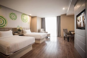 Ein Hotelzimmer mit zwei Betten, einem Sessel, einem Fernseher und einer Wand mit kreisförmigen Mustern.