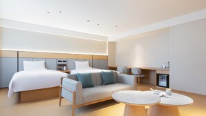 Une chambre d’hôtel moderne équipée d’un lit, d’un canapé, de deux petites tables rondes et d’une kitchenette.