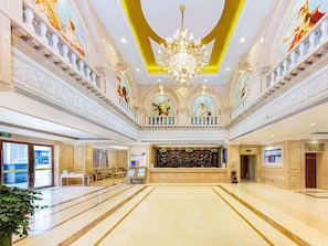 Un hall d’hôtel spacieux, agrémenté d’un magnifique lustre, de sols en marbre et d’œuvres d’art classiques accrochées aux murs.