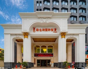 L’entrée d’un hôtel, avec une enseigne bien visible, de grandes colonnes et un panneau d’affichage numérique.