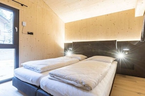 A room with two beds, wooden walls, a large window, and a modern headboard with lights. - Superior Chalet #14 with Sauna & Hot Tub (Turrach)