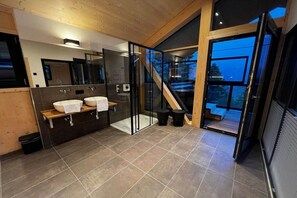 A modern bathroom with two sinks, a glass shower enclosure, and a view of the outdoors.