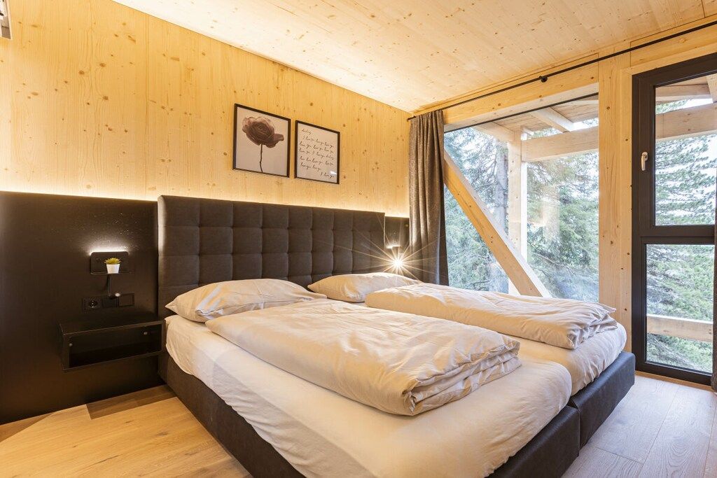 A bedroom with a large bed, a nightstand, and a window with curtains.
