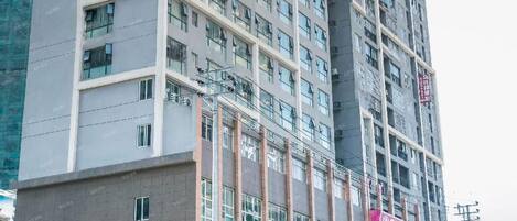 Un hotel de varios pisos con un letrero llamativo en la fachada, múltiples ventanas y una zona comercial en la planta baja con diversas tiendas.