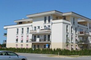 Ein mehrstöckiges Wohngebäude mit Balkonen, einem Parkschild und blauem Himmel.