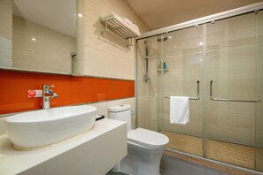 Un bagno con lavandino bianco, WC e box doccia in vetro.