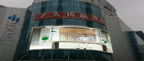 A hotel with a prominent sign for '7天优品酒店' and a lower sign for '海澜之家'.