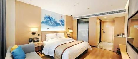 A hotel room with a bed, bedside tables, a sofa, a painting, and a mirror.