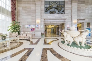 A lobby with marble flooring, a reception desk, a chandelier, and a decorative sculpture.