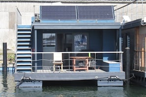 A floating house with a deck, a table, and a chair.
