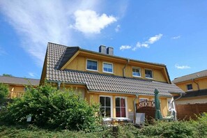 Ein zweigeschossiges Haus mit einem Ziegeldach, zahlreichen Fenstern und einem sichtbaren Schornstein.