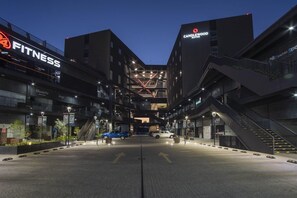 Un edificio de varios pisos con un gimnasio en la planta baja, un hotel llamado 'CANDLEWOOD SUITES' en los pisos superiores y un atrio central con una escalera.