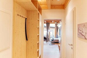 A hallway with wooden walls and a door leading to a living area with a sofa and a lamp. - Cabin in Niederwölz with sauna (Niederwölz)