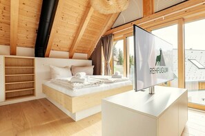 A modern bedroom with a loft bed, a flat-screen TV, and a view of the outside. - Cabin in Niederwölz with sauna (Niederwölz)