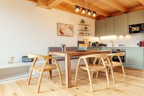 Eine moderne Küche mit Holzboden, einem Esstisch mit Stühlen und einer Pendelleuchte.