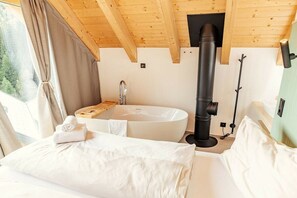 Ein Schlafzimmer mit einem großen Bett, einer Badewanne und einer Sauna.