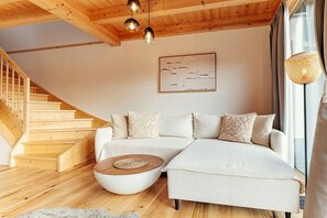 Ein modernes Wohnzimmer mit einer Holztreppe, einem weißen Sofa und einem runden Couchtisch.