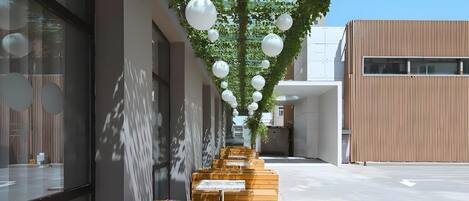 A modern building with a wooden bench area, white spherical decorations, and a clear sky.