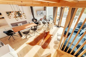 Ein modernes Interieur mit einem Holzesstisch, schwarzen Stühlen, einem Lederteppich und einem blauen Sofa.