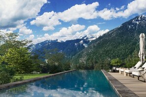 Ein Pool mit Blick auf die Berge, Liegestühle und ein Holzdeck.