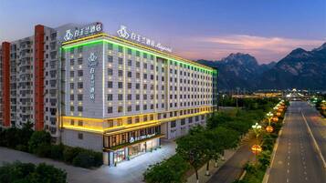 A multi-story hotel with a prominent entrance and a view of mountains in the background.