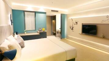 A modern hotel room with a large bed, a television, a small desk, and a bathroom.