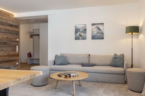 A modern living room with a sofa, a round coffee table, and two wall-mounted paintings. - Apartment with 1 bedroom (St. Martin am Tennengebirge)