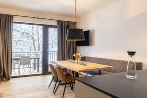 A modern dining area with a wooden table, chairs, and a black pendant light. - Apartment with 1 bedroom (St. Martin am Tennengebirge)