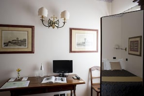 Una habitación con escritorio, cama y dos cuadros en la pared.