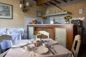 Un comedor con una mesa dispuesta para cuatro personas, una encimera de cocina con electrodomésticos y una pared decorativa.