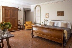 Un dormitorio con una cama de madera, una silla, una mesa con un florero y un armario.