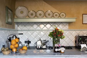A kitchen with a juicer, a coffee machine, and a vase with flowers.
