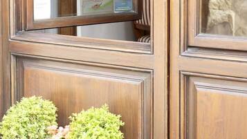 A wooden door with a glass window displaying the text 'LE CANNELLE bed & breakfast AFFITTACAMERE.'